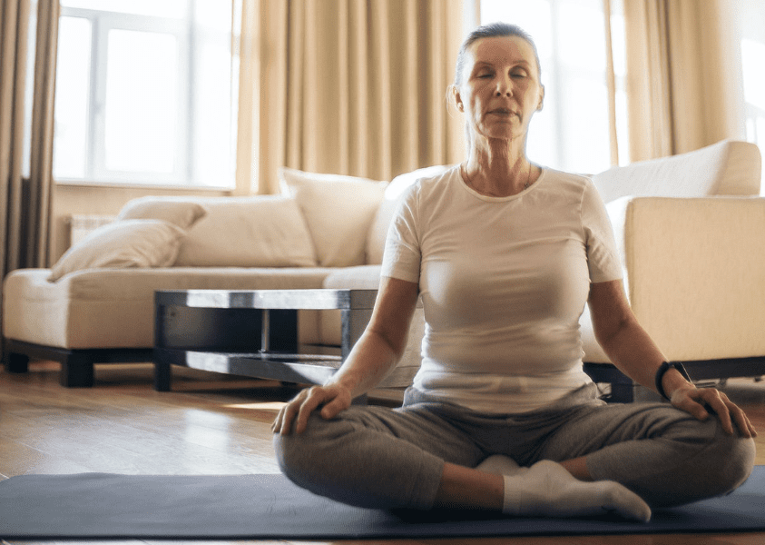 Uma senhora sentada meditando representando atenção plena