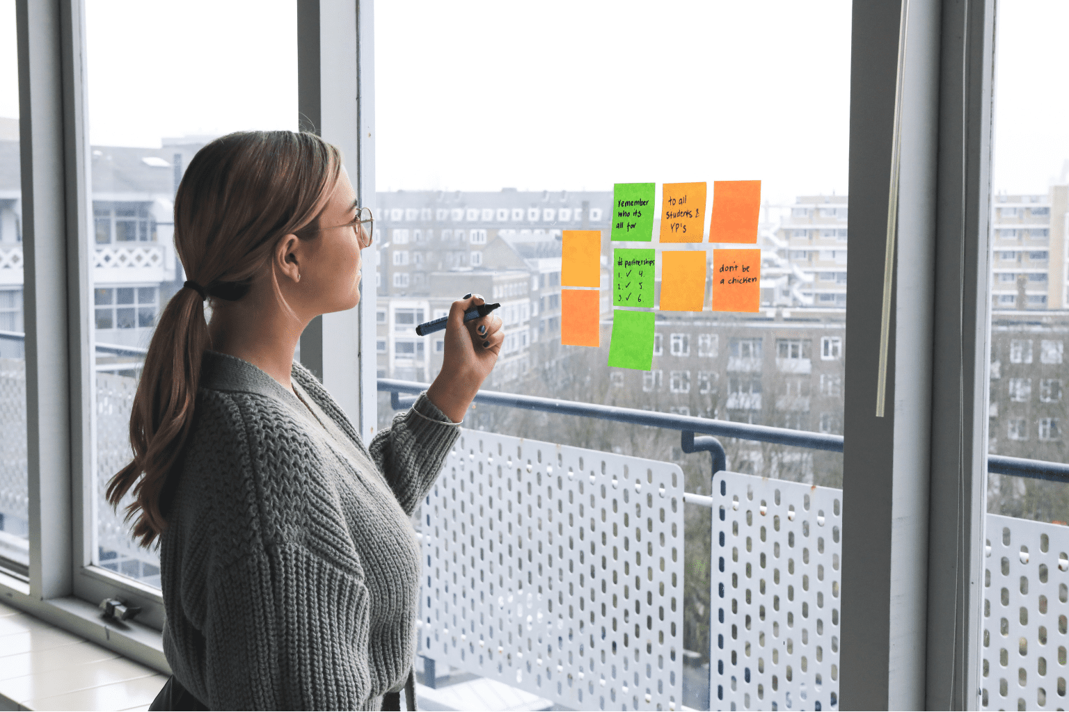 Pessoa olhando post-it e colados em uma janela aparentemente de escritorio